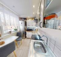 Kuchyně v 2pokojovém bytě s jídelním koutem, skříňkami a velkým oknem.