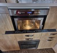 Mikrovlnná trouba v chatě s podlahou s dřevěným dekorem a kuchyňskou linkou.