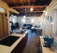 Chata s dřevěnými prvky a kachlemi, podlaha s dřevěným dekorem, kuchyňský ostrůvek.