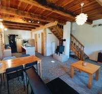 Interiér chaty s podlahou s dřevěným dekorem, dřevěným stropem a kachlovými kamny.