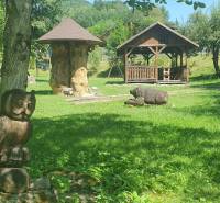 Zahrada na Hviezdoslavově ulici v Tisovci s dřevěnými sochami u chaty.