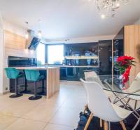 Světlá kuchyně s jídelním stolem a barovými židlemi v rodinném domě.