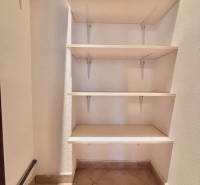 Úložný prostor s policemi a dlažbou ve 3-pokojovém bytě.