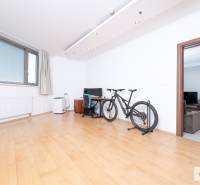 Pokoj v 3-pokojovém bytě s kolem, pracovním stolem a podlahou s dřevěným dekorem.