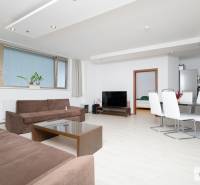 Světlý obývací pokoj v třípokojovém bytě s pohovkou a jídelním stolem.