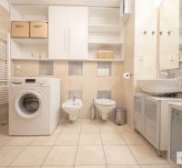 Koupelna ve 3-pokojovém bytě s pračkou, toaletou a bidetem, s dlažbou a skříňkami.