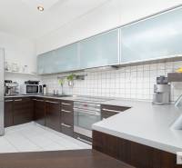 Kuchyně v 3-pokojovém bytě s bílými dlaždicemi a tmavými skříňkami.