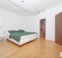 Ložnice v třípokojovém bytě s postelí, podlahou s dřevěným dekorem a vestavěnou skříní.