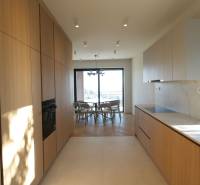 Kuchyně ve 4-pokojovém bytě s podlahou s dřevěným dekorem a světlou kuchyňskou linkou.