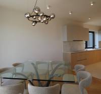 Jídelna se skleněným stolem a židlemi, 4pokojový byt, podlaha s dřevěným dekorem.