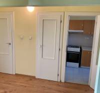 Interiér 3-pokojového bytu s podlahou s dřevěným dekorem a kuchyňskou linkou.