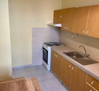 Kuchyně v 3-pokojovém bytě s plynovým sporákem a dřevěnými skříňkami.