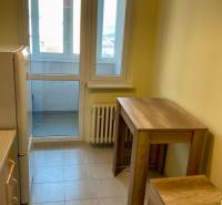 Kuchyně v 3-pokojovém bytě s velkými okny, barovým stolem a židlemi.