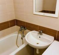 Koupelna s vanou, umyvadlem a pračkou v 3-pokojovém bytě, světlé obklady.