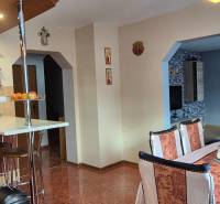 Jídelna v rodinném domě s dřevěnými prvky, stolem a židlemi, světlý interiér.