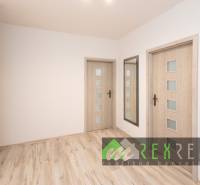 Chodba v 3-pokojovém bytě s podlahou s dřevěným dekorem a zrcadlem.