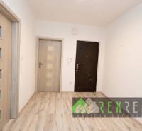 Interiér 3-pokojového bytu s podlahou s dřevěným dekorem a bílými stěnami.