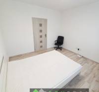 Světlá ložnice ve 3-pokojovém bytě s podlahou s dřevěným dekorem a kancelářskou židlí.