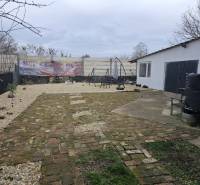 Dvůr rodinného domu v Hernádkaku s dlažbou a venkovním posezením na pozemku.