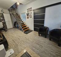 Interiér rodinného domu s moderním schodištěm a podlahou s dřevěným dekorem.