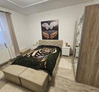 Ložnice s postelí, skříní a podlahou s dřevěným dekorem v rodinném domě.