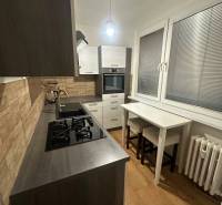 Kuchyně v 2-pokojovém bytě s podlahou s dřevěným dekorem a plynovým sporákem.