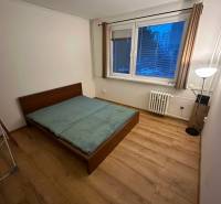 Ložnice v 2-pokojovém bytě s postelí a podlahou s dřevěným dekorem.