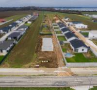 Stavební pozemek v Sokolovcích vedle řady novostaveb rodinných domů.