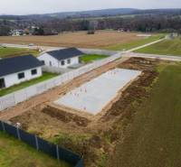 Základy rodinného domu v Sokolovcích, obklopené poli a sousedními domy.