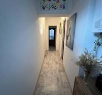 Úzká chodba v rodinném domě s dekorací dětských rukou a podlahou s dřevěným dekorem.