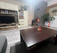 Obývací pokoj v rodinném domě s krbem a nábytkovou stěnou, podlaha s dřevěným dekorem.