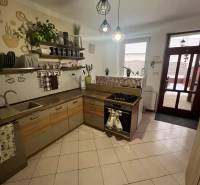 Kuchyně v rodinném domě s keramickou dlažbou, dřevěnými dekoracemi a otevřenými policemi.