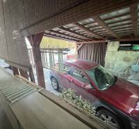 Červené auto zaparkované pod přístřeškem u rodinného domu na Dubovské ulici ve Zvolenu.