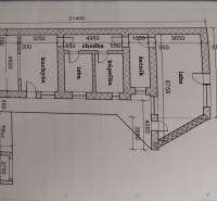 Půdorys rodinného domu s několika pokoji, kuchyní, koupelnou a přístřeškem pro auto.