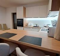 Kuchyně v 2pokojovém bytě s vestavěnými spotřebiči a podlahou s dřevěným dekorem.