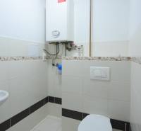 Koupelna v 2-pokojovém bytě s kotlem a toaletou, obložená keramickými dlaždicemi.