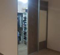 Šatník s posuvnými dveřmi a podlahou s dřevěným dekorem v rodinném domě.