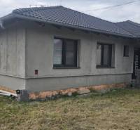 Rodinný dům z neomítnutých zdí v Semerově s šindelovou střechou na travnatém pozemku.