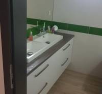 Koupelna v rodinném domě s umyvadlem a podlahou s dřevěným dekorem.