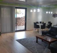 Obývací pokoj v rodinném domě s podlahou s dřevěným dekorem, pohovkou a jídelním stolem.