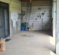 Interiér rodinného domu s nevkusnými stěnami, žebříkem a stavebním materiálem.