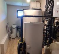 Technická místnost v rodinném domě s kotlem, nádržemi a podlahou s dřevěným dekorem.