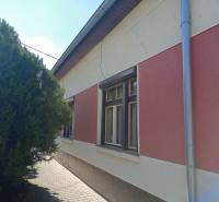 Rodinný dům v Nových Zámcích se sítěmi na zateplené fasádě a stromem u chodníku.