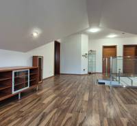 Podkrovní prostor v rodinném domě s podlahou s dřevěným dekorem a vestavěnými skříňkami.