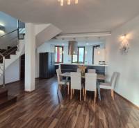 Interiér rodinného domu s kuchyní, jídelnou a schodištěm na podlaze s dřevěným dekorem.