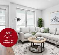 Světlý obývací pokoj s pohovkou, podlahou s dřevěným dekorem a rostlinami v 2-pokojovém bytě.