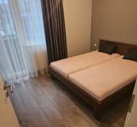 Ložnice v 3-pokojovém bytě s podlahou s dřevěným dekorem a manželskou postelí.