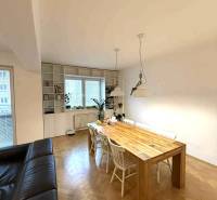 Jídelní stůl ve čtyřpokojovém bytě s podlahou s dřevěným dekorem a bílými židlemi.