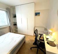 Ložnice ve 4-pokojovém bytě s bílým nábytkem a podlahou s dřevěným dekorem.