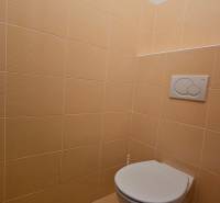 Toaleta s béžovými dlaždicemi v obchodních prostorách.